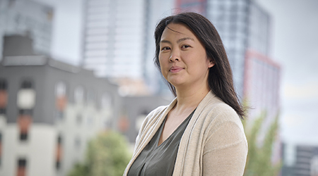 Diana Pascua, a woman in a tan shirt standing in front of a city.